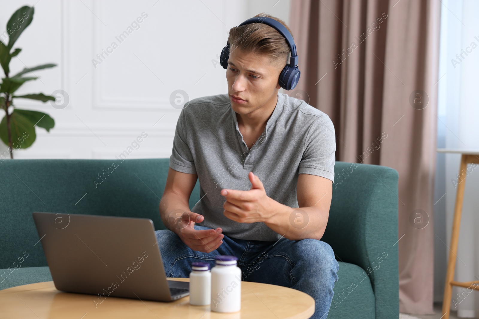 Photo of Man in headphones having online consultation with doctor via laptop at home