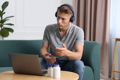 Photo of Man in headphones having online consultation with doctor via laptop at home