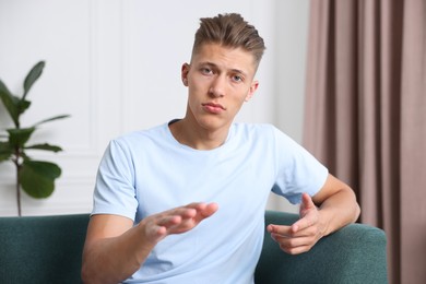 Photo of Portrait of sad man on sofa at home. Online medical consultation