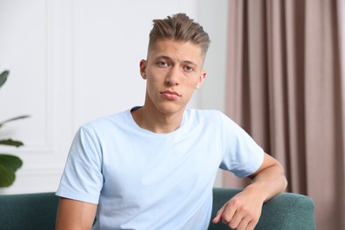 Photo of Portrait of sad man on sofa at home. Online medical consultation