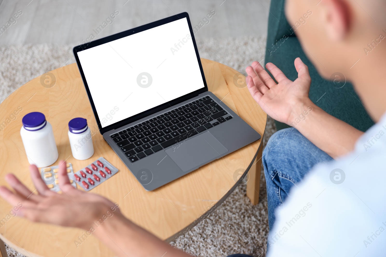Photo of Man having online consultation with doctor via laptop at home, above view
