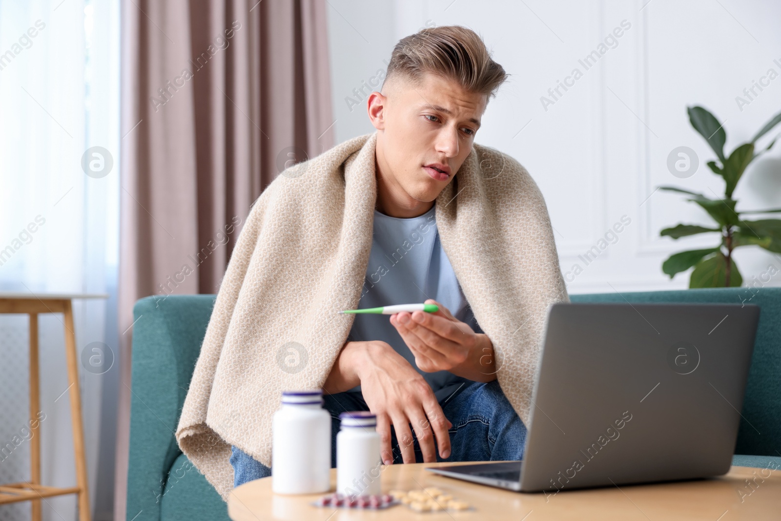 Sick man with thermometer having online consultation with doctor via laptop at home Photo of Sick man with thermometer having online consultation with doctor via laptop at home