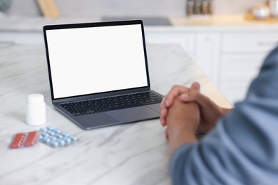 Photo of Man having online consultation with doctor via laptop at table in kitchen, closeup
