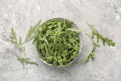 Photo of Fresh ripe green arugula leaves in bowl on grey table, flat lay