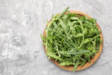 Photo of Fresh ripe green arugula leaves on grey table, top view. Space for text