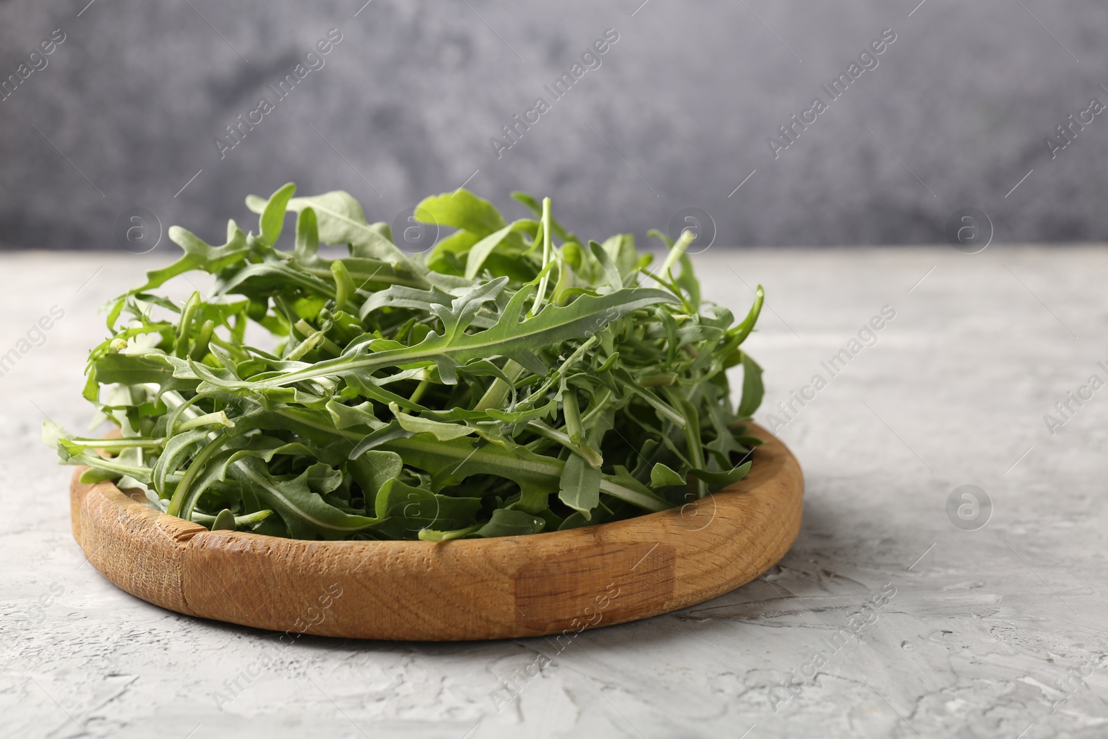 Fresh ripe green arugula leaves on grey table, closeup Photo of Fresh ripe green arugula leaves on grey table, closeup