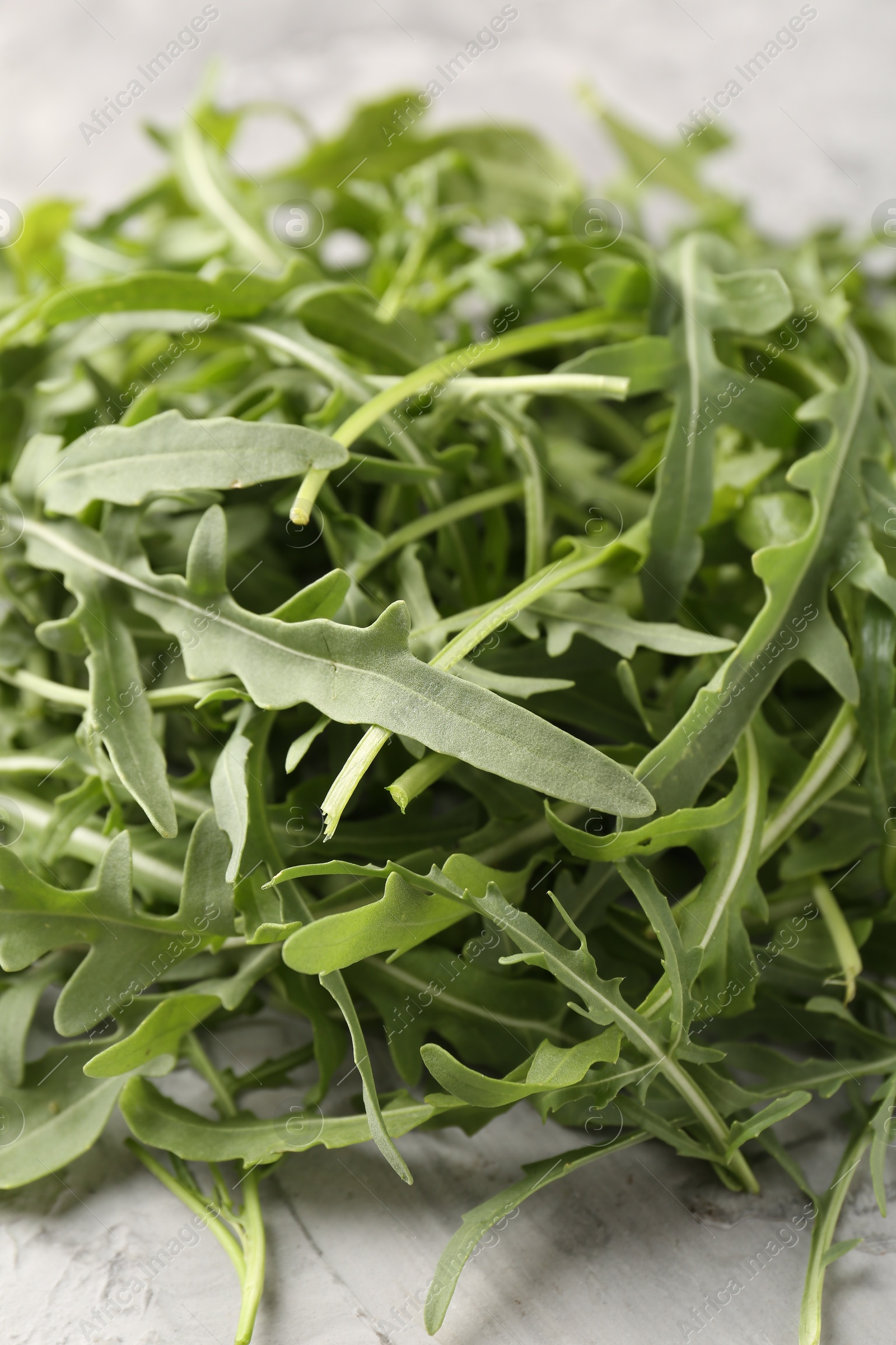 Fresh ripe green arugula leaves on grey table, closeup Photo of Fresh ripe green arugula leaves on grey table, closeup