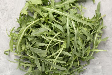 Photo of Fresh ripe green arugula leaves on grey table, top view