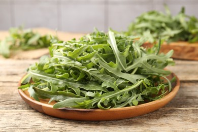 Photo of Fresh ripe green arugula leaves on wooden table, closeup