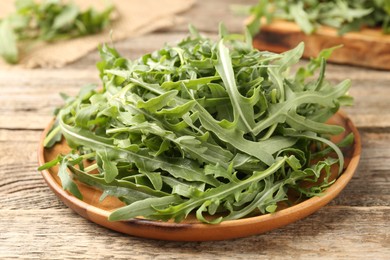 Photo of Fresh ripe green arugula leaves on wooden table, closeup