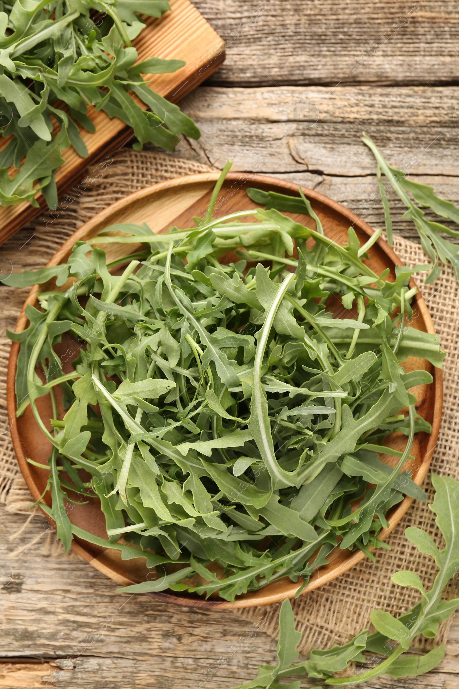 Photo of Fresh ripe green arugula leaves on wooden table, flat lay