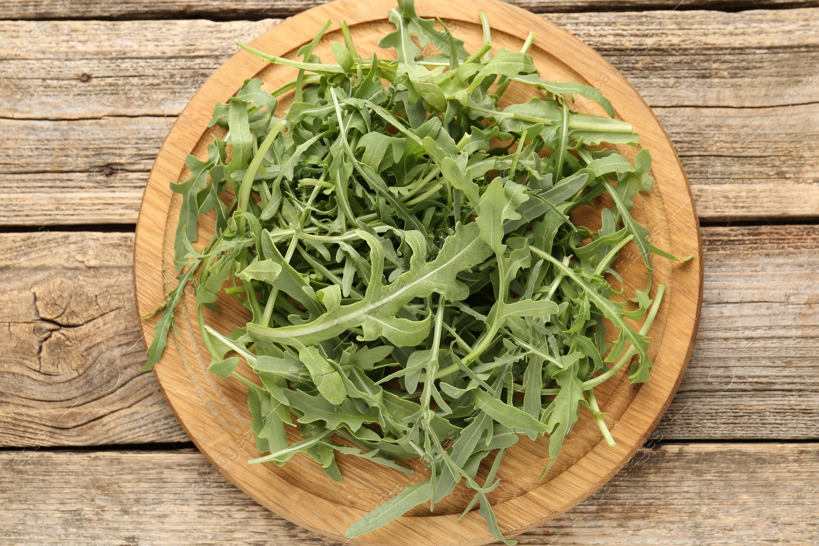 Fresh ripe green arugula leaves on wooden table, top view Photo of Fresh ripe green arugula leaves on wooden table, top view