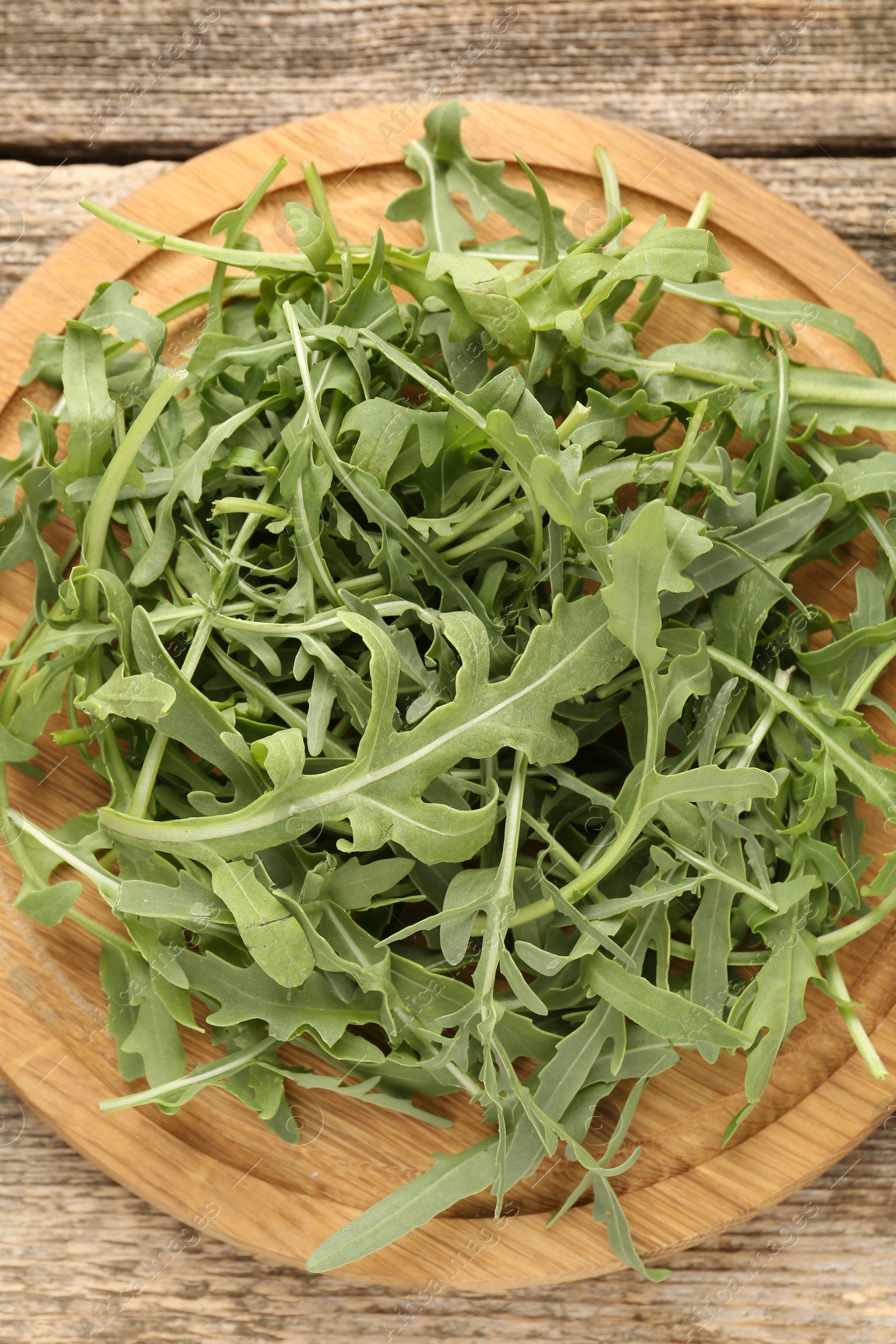Fresh ripe green arugula leaves on wooden table, top view Photo of Fresh ripe green arugula leaves on wooden table, top view