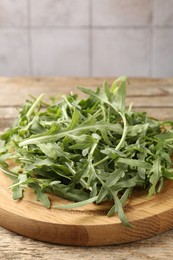Photo of Fresh ripe green arugula leaves on wooden table, closeup