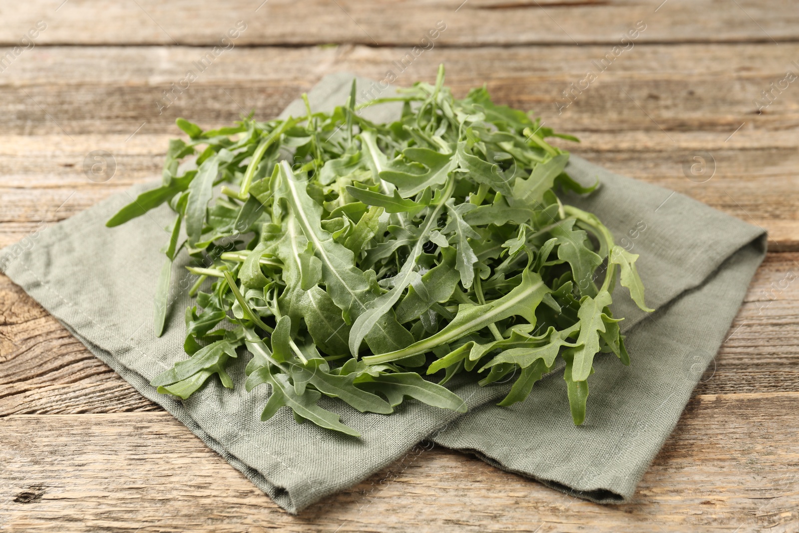 Fresh ripe green arugula leaves on wooden table, closeup Photo of Fresh ripe green arugula leaves on wooden table, closeup