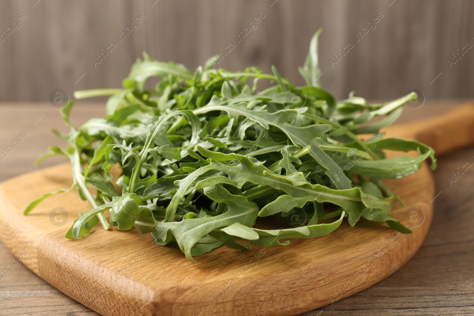 Fresh ripe green arugula leaves on wooden table, closeup Photo of Fresh ripe green arugula leaves on wooden table, closeup