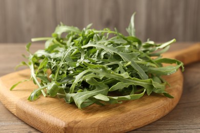 Photo of Fresh ripe green arugula leaves on wooden table, closeup