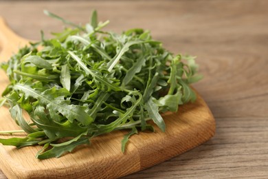 Photo of Fresh ripe green arugula leaves on wooden table, closeup