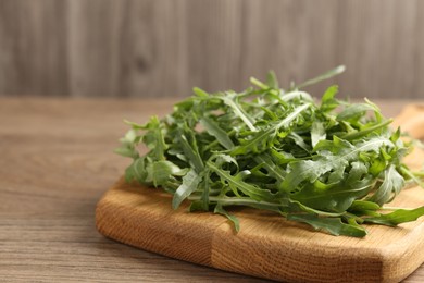 Photo of Fresh ripe green arugula leaves on wooden table, closeup. Space for text