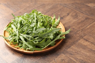 Photo of Fresh ripe green arugula leaves on wooden table, closeup. Space for text