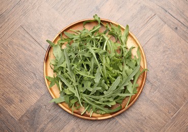 Photo of Fresh ripe green arugula leaves on wooden table, top view