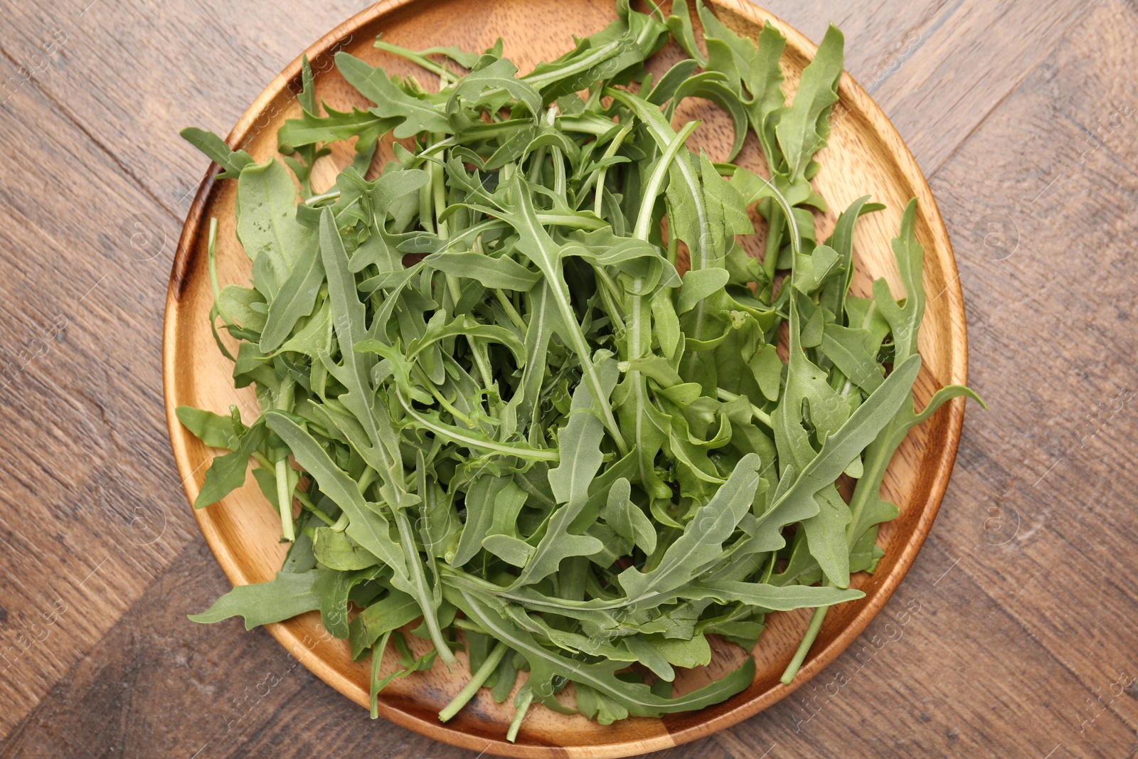 Photo of Fresh ripe green arugula leaves on wooden table, top view