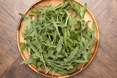 Photo of Fresh ripe green arugula leaves on wooden table, top view