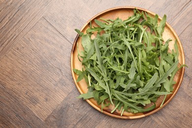 Photo of Fresh ripe green arugula leaves on wooden table, top view. Space for text