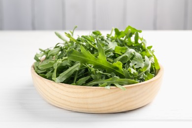 Photo of Fresh ripe green arugula leaves on white wooden table, closeup