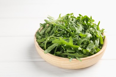 Photo of Fresh ripe green arugula leaves on white wooden table, closeup. Space for text