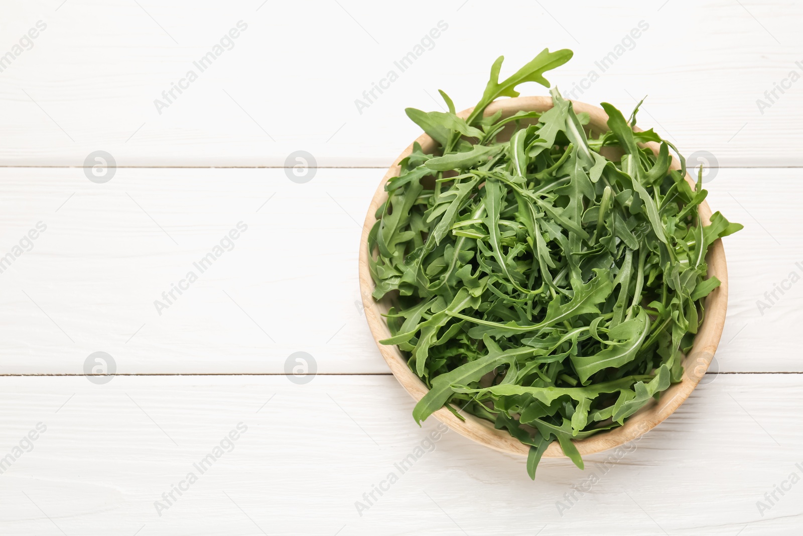 Fresh ripe green arugula leaves on white wooden table, top view. Space for text Photo of Fresh ripe green arugula leaves on white wooden table, top view. Space for text