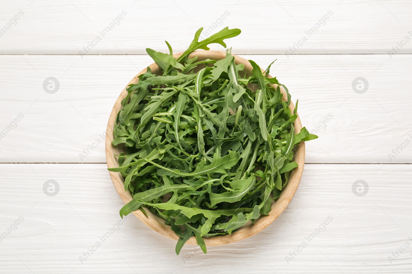 Fresh ripe green arugula leaves on white wooden table, top view Photo of Fresh ripe green arugula leaves on white wooden table, top view