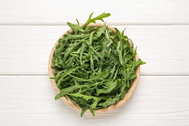 Photo of Fresh ripe green arugula leaves on white wooden table, top view