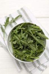 Photo of Fresh ripe green arugula leaves in bowl on white wooden table, top view