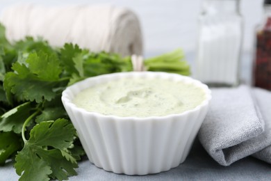 Photo of Tasty cilantro sauce in bowl on grey table, closeup