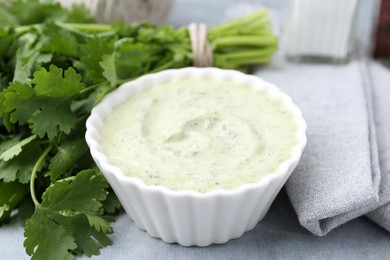 Photo of Tasty cilantro sauce in bowl on grey table, closeup