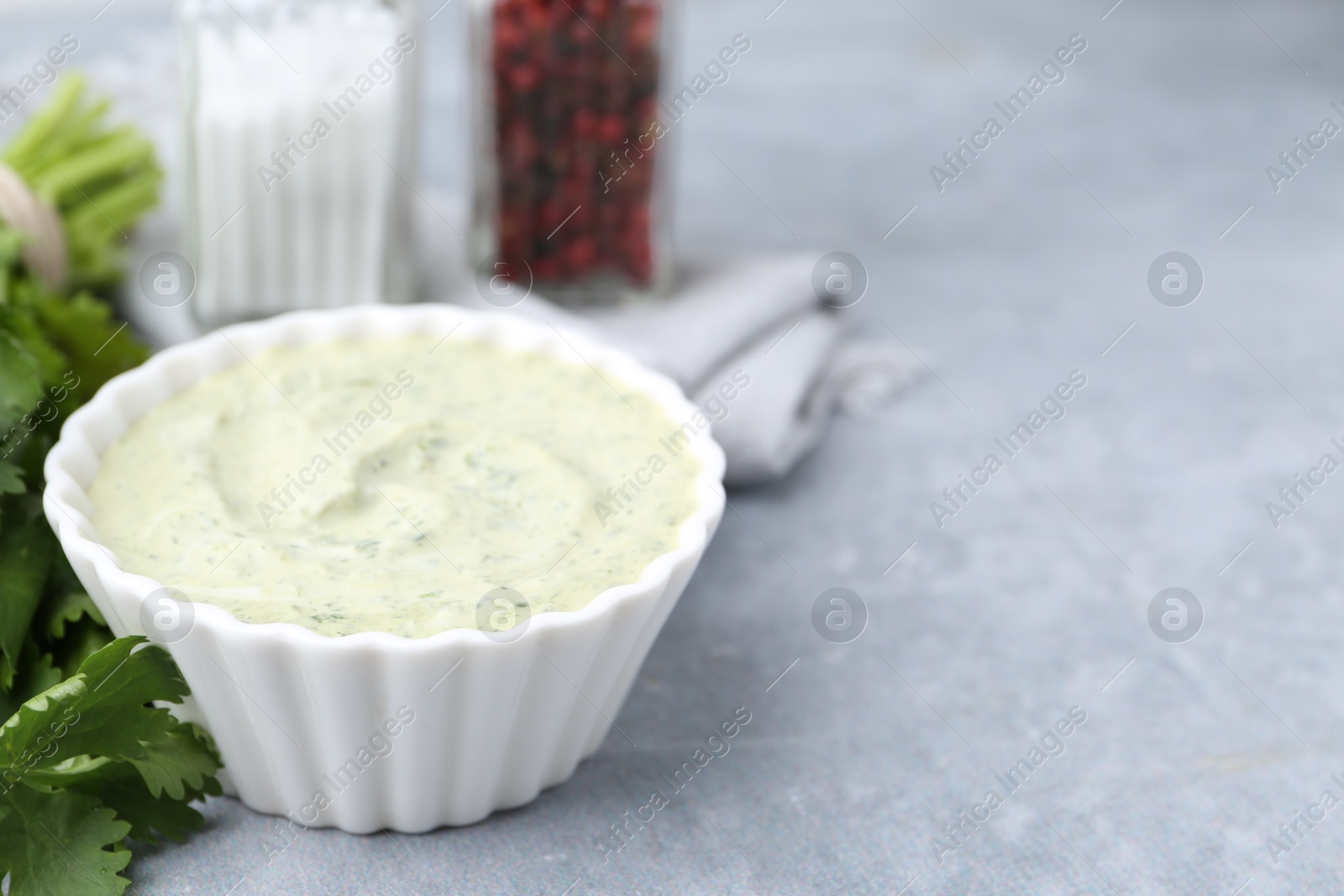 Photo of Tasty cilantro sauce in bowl on grey table, closeup. Space for text