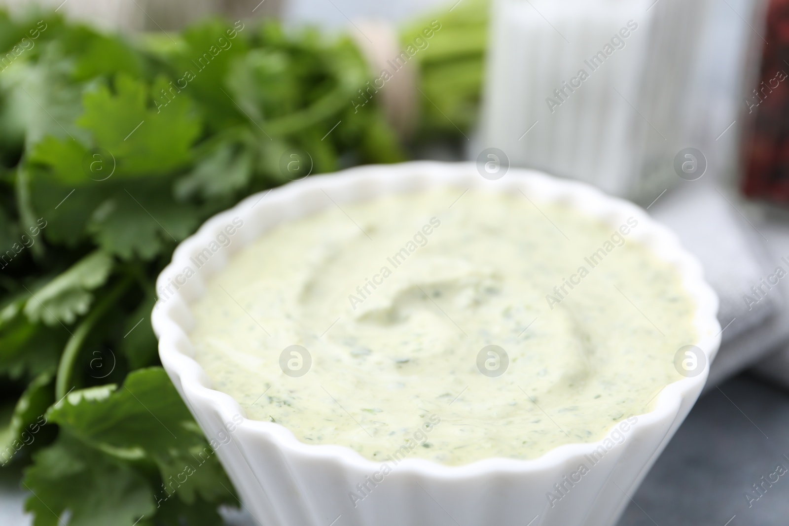 Photo of Tasty cilantro sauce in bowl on grey table, closeup