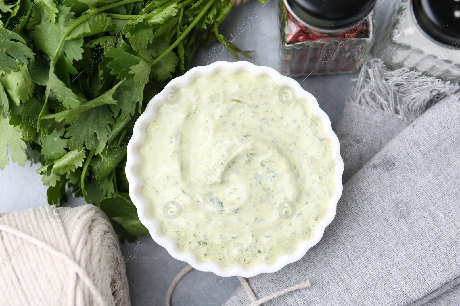 Tasty cilantro sauce in bowl and spices on grey table, flat lay Photo of Tasty cilantro sauce in bowl and spices on grey table, flat lay