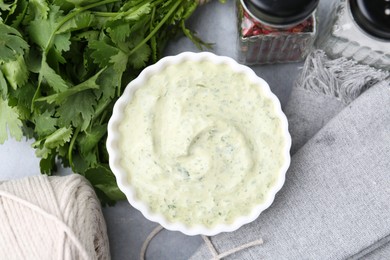 Photo of Tasty cilantro sauce in bowl and spices on grey table, flat lay