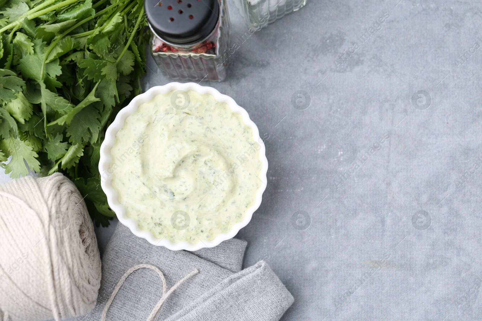Tasty cilantro sauce in bowl and spices on grey table, flat lay. Space for text Photo of Tasty cilantro sauce in bowl and spices on grey table, flat lay. Space for text