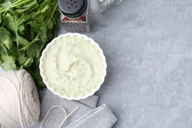 Photo of Tasty cilantro sauce in bowl and spices on grey table, flat lay. Space for text
