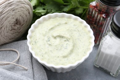 Photo of Tasty cilantro sauce in bowl and spices on grey table, closeup