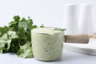 Photo of Tasty cilantro sauce on light grey table, closeup