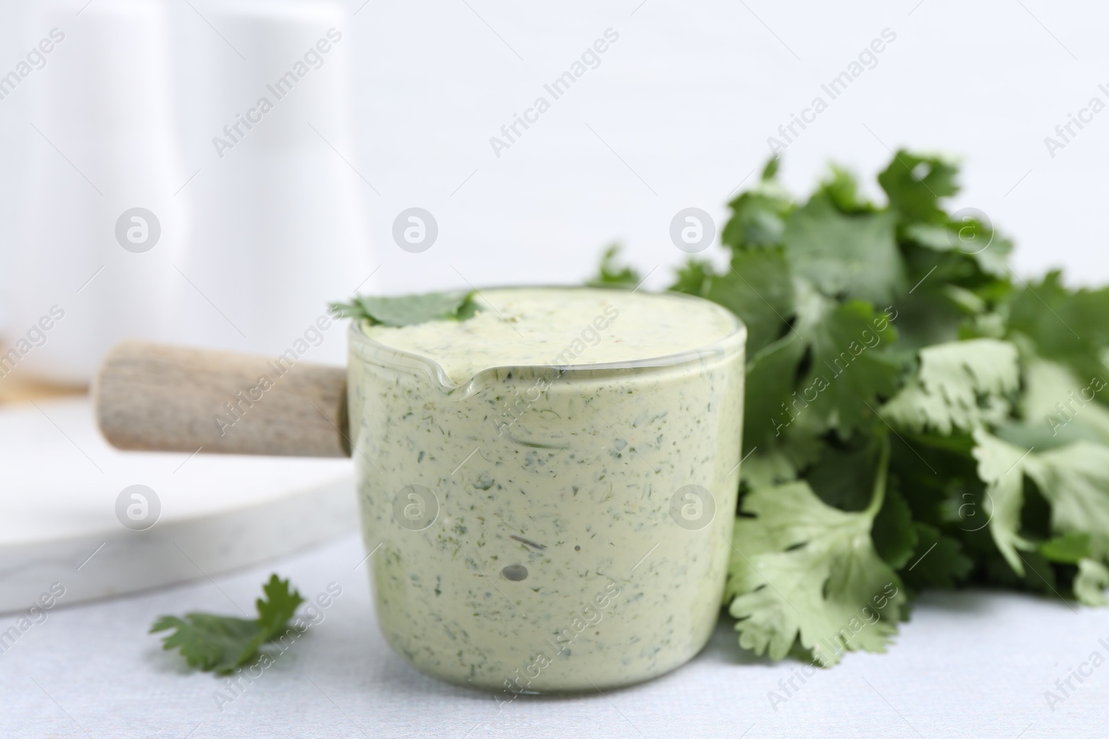 Tasty cilantro sauce on light grey table, closeup Photo of Tasty cilantro sauce on light grey table, closeup