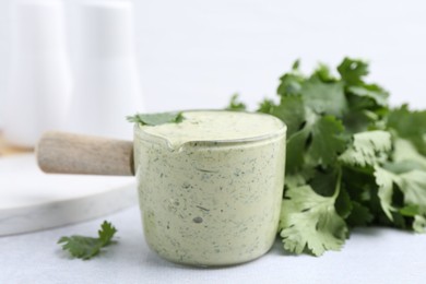 Photo of Tasty cilantro sauce on light grey table, closeup
