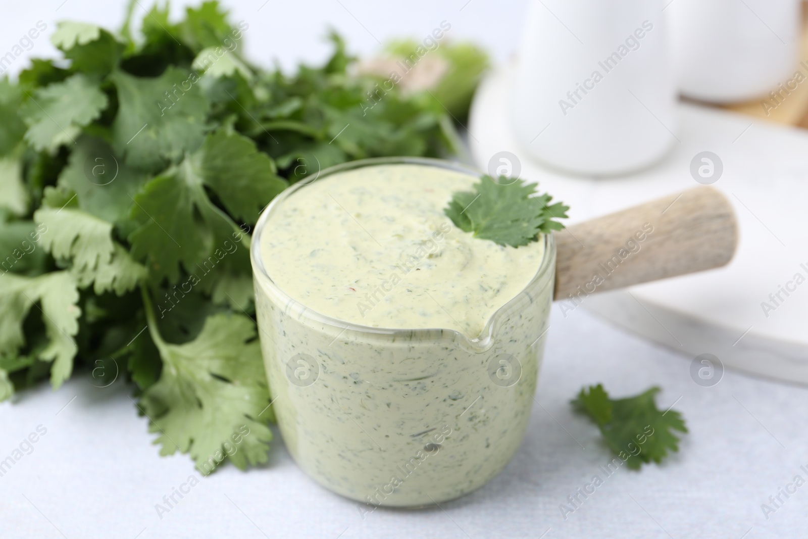 Tasty cilantro sauce on light grey table, closeup Photo of Tasty cilantro sauce on light grey table, closeup