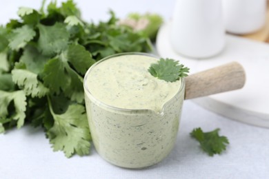 Photo of Tasty cilantro sauce on light grey table, closeup