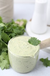 Photo of Tasty cilantro sauce on light grey table, closeup