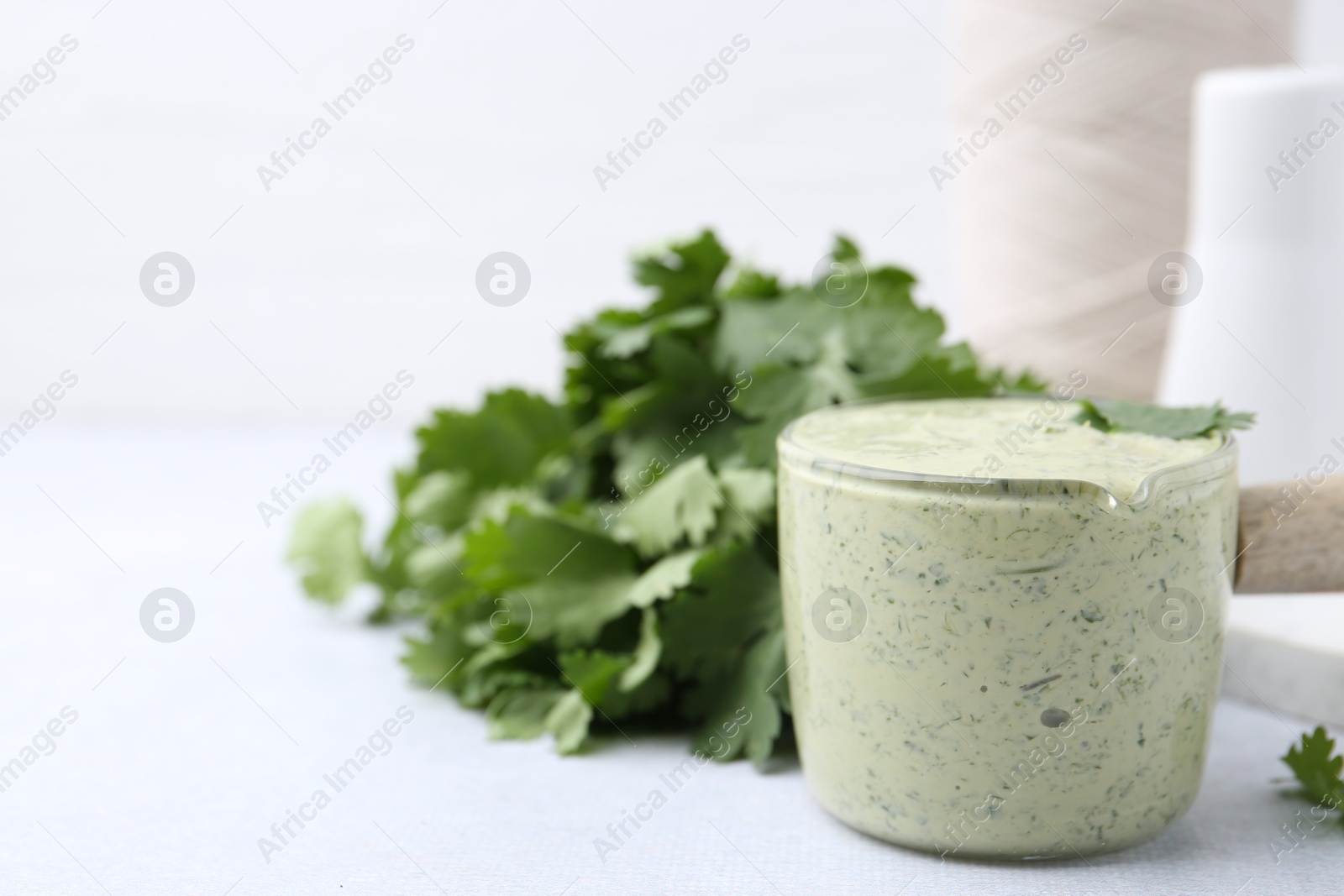 Tasty cilantro sauce on light grey table, closeup. Space for text Photo of Tasty cilantro sauce on light grey table, closeup. Space for text